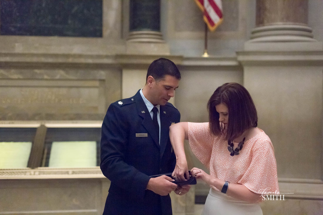 Wife pinning on the rank of her military husband in the National Archives in Washington D.C.