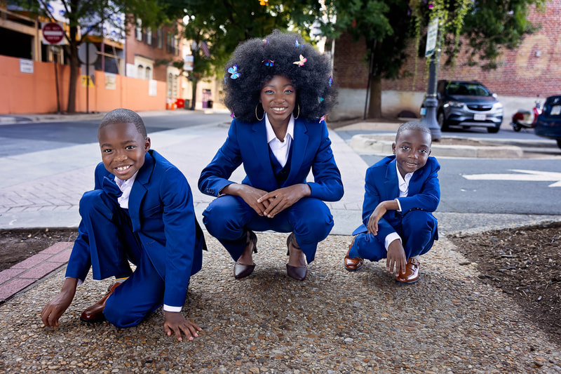 Behold the timeless elegance and charm captured in this stunning photograph of three siblings dressed in matching blue suits with white shirts, taken by the talented family photographer Tamieka Smith in Northern Virginia. The siblings' poised and confident poses exude a sense of maturity and grace, highlighting their strong bond and the love they share. Tamieka's skillful use of framing and composition highlights the rich history and beauty of Manassas, with its striking architecture and historic buildings serving as a magnificent backdrop for the siblings. Her use of light and color further enhances the scene, with the warm glow of the sun casting a golden hue and emphasizing the siblings' natural radiance. This photograph is a tribute to the enduring bond of sibling relationships, the power of love and connection, and the beauty and majesty of the world around us. It's a cherished memory that the siblings and their loved ones will treasure for generations to come, a symbol of the strength and resilience that unites us all.
