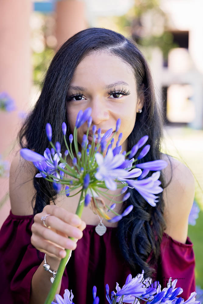 LMU graduate smelling flowers on campus