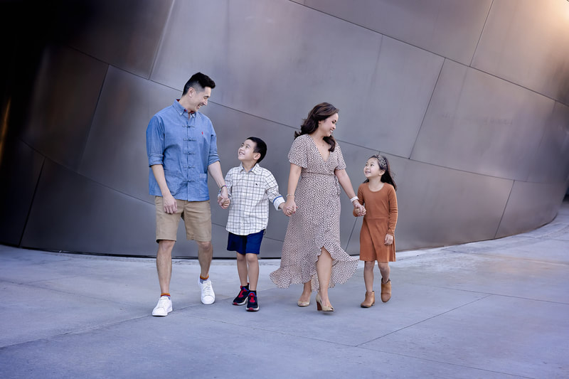 An enchanting family portrait session of four family members at the iconic Los Angeles Disney Concert Hall, captured by the skilled eye of Tamieka Smith, a Los Angeles Family Photographer in Torrance. The image features the family standing in front of the striking architectural backdrop of the concert hall, with its mesmerizing curves and metallic sheen. The family members are dressed in coordinating outfits that complement the metallic tones of the setting, and the image is framed to include the entire family from head to toe. This unique and magical photoshoot location adds an extra dimension to the family portrait, making it a stunning and memorable keepsake for years to come.