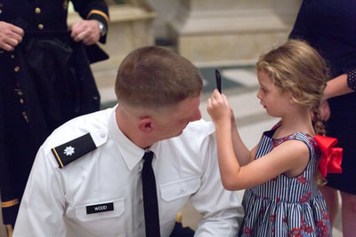 Tamieka Smith Photography captures a heartwarming moment as a daughter proudly pins a new rank on her father's Navy uniform at a promotion ceremony at the National Archives in Washington D.C. Tamieka's expert eye for detail and her ability to capture authentic emotion ensure that this unforgettable moment will be remembered for a lifetime. Hire Tamieka to document your Navy promotion ceremony, and you'll receive exceptional, high-quality images that celebrate the pride and accomplishments of the Navy community. Trust Tamieka to skillfully document each aspect of the ceremony, from the official proceedings to the personal moments of joy and celebration. Tamieka Smith Photography is the perfect choice to make your Navy promotion ceremony unforgettable.