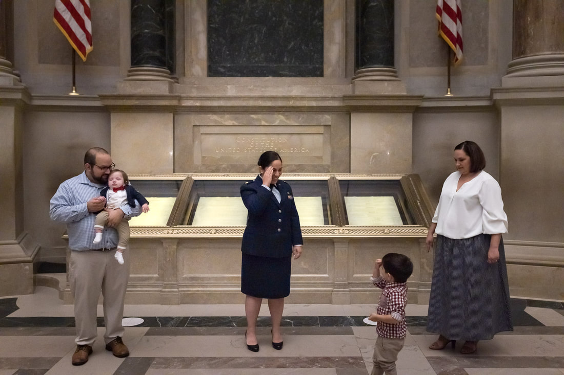 Military member salutes her during the National Archives promotion ceremony